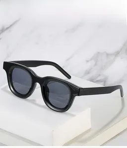 Detail of oval black polished sunglasses with dark grey lenses on marble background