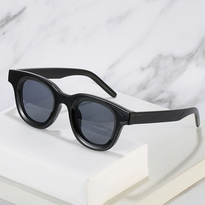 Retro oval black frame sunglasses with dark grey lenses on white marble background