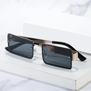 Modern rectangle sunglasses with gold metal frame and dark grey lenses on white platform