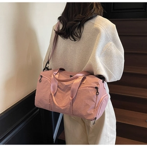 Back view of pink large canvas travel bag with wide shoulder strap on wooden stairs