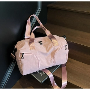 Detail of pink nylon duffel bag with wide straps and matte black zippers on stairs