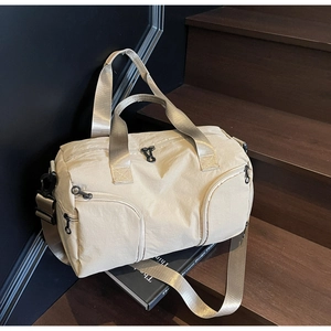 Detail view of a beige canvas travel bag with black hardware on a wooden background