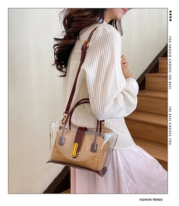 Detail of transparent PVC tote bag with straw lining and deep red leather handles