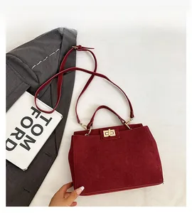 Detailed close-up of dark red frosted leather handbag with elegant gold metal twist lock