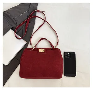 Deep red suede handbag size comparison showing metal twist lock and dimensions