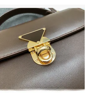 Detailed close-up of premium dark brown leather texture and golden metal clasp on handbag
