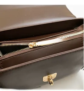 Detailed macro view of the smooth golden zipper and hardware on brown leather bag