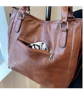 Detail view of the brown vintage tote bag showing the secure metal back zipper pocket