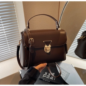 Detail of dark coffee vintage shoulder bag with a unique triangle metal lock and leather texture