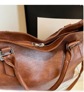 Detail shot of smooth metal zipper and leather texture on a brown tote bag