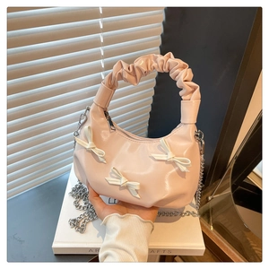 Detail of light pink crescent bag with white bows and pleated handle with silver chain