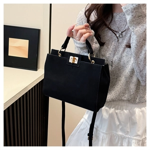 Detail of vintage matte black handbag with golden square lock on a model