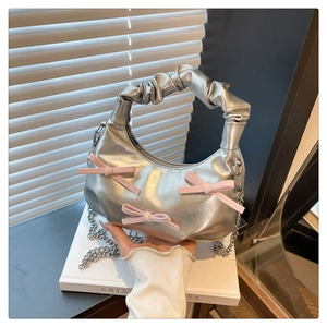 Detail of silver metallic handbag with pink bows, pleated handle and chain strap