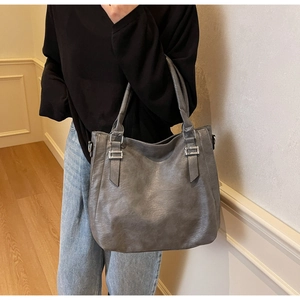 Detail of gray soft PU leather tote bag with silver metal buckles and dual handles