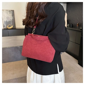 Detail of dark red matte tote bag with handle and metal buckle shown on a shoulder