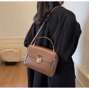 Detail of vintage brown crossbody bag featuring triangle metal lock and side zippers