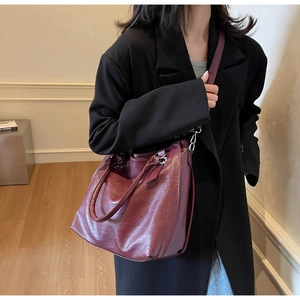 Detail of burgundy leather tote bag with lychee texture and metallic strap buckles