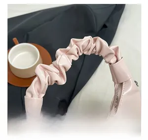 Detail shot of a light pink pleated handbag handle with elegant PU leather finish