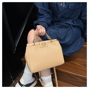Close-up of beige lychee grain leather bag with golden metal twist lock and adjustable strap