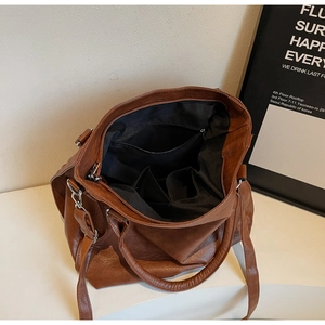 Internal view of brown tote bag showing black lining, zip pocket, and spacious interior