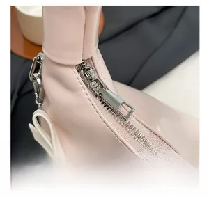 Detail of silver zipper and white bow decoration on light pink pleated shoulder bag