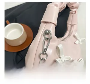 Detailed shot of pink pleated handbag with white bow and silver chain hardware accents