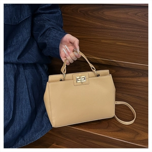 Close-up of beige lychee grain leather handbag with golden twist-lock and top handle