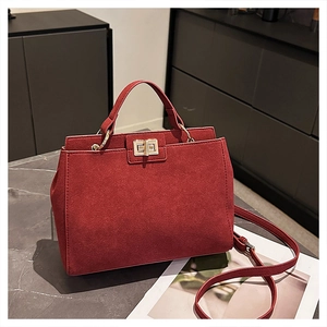 Detail of burgundy suede handbag with golden twist lock and metallic ring handle