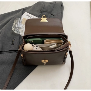 Detail of spacious dark brown crossbody bag interior with multiple compartments and gold buckle