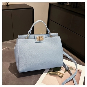 Close-up of light blue pebbled leather handbag with gold metal clasp and top handle
