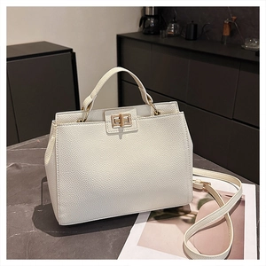 Close-up of white lychee-patterned tote bag with golden metal twist lock and sturdy handle