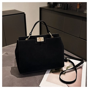 Detail of black matte tote bag with gold metal clasp on a grey marble surface