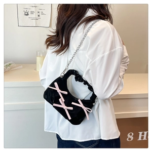 Chic black pleated hobo bag with pink bows shown in a stylish cafe scene model view
