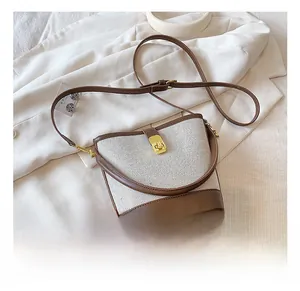Detailed view of bucket bag with cream woven texture, brown leather trim and gold twist lock