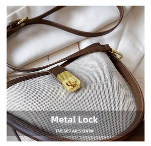 Close-up of golden rectangle metal twist lock on a woven bucket bag with leather trim