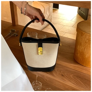 Detail showing the vintage canvas bucket bag with black leather trim and gold metal lock