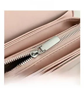 Detailed close-up of smooth silver metal zipper on pink leather bag with brown lining