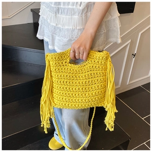 Detail der gelben handgewebten Häkeltasche mit langen Fransen und strukturierter Strickoptik