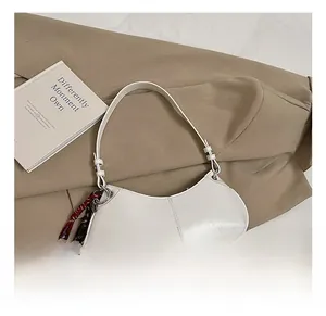 Detail showing the white semi-circular leather hobo bag with a woven decorative lanyard strap