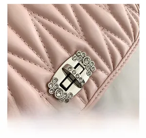 Close-up of pink quilted leather bag featuring a silver twist lock with sparkling rhinestones