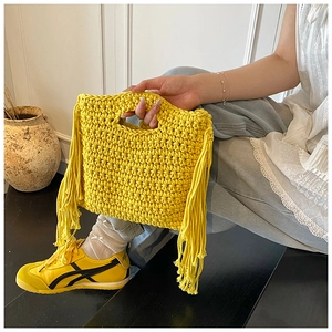 Detail der gelben handgehäkelten Handtasche mit langen Seitenfransen und Webstruktur