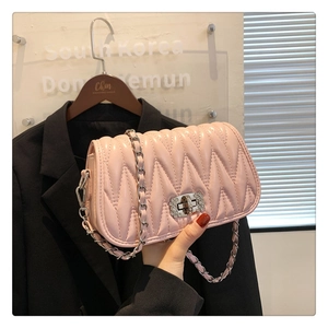 Detail of light pink quilted handbag with silver chain and crystal studded turn-lock
