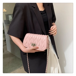 Detail of light pink quilted chain bag with rhinestone lock worn by model