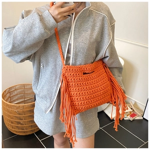 Detail der orangefarbenen Web-Schultertasche mit langen Fransen und Strickstruktur