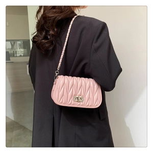 Detail of light pink quilted crossbody bag with rhinestone buckle and chain strap