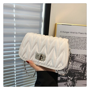 Detailed view of white quilted faux leather bag with crystal lock and chain strap