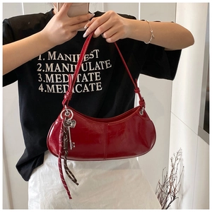 Detail of red patent leather moon bag with silver key charm and decorative ribbon