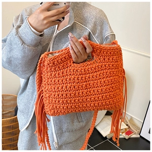 Detail der orangefarbenen Häkeltasche mit Fransen und Schultergurt im Boho-Stil