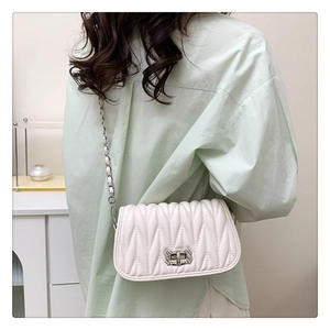 Detail of soft cream quilted handbag with rhinestone silver clasp and chain strap