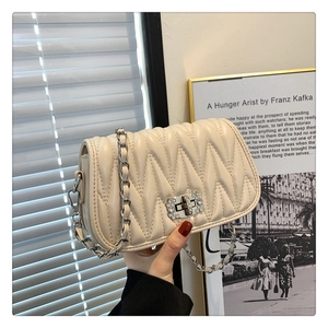 Detail of cream quilted handbag with rhinestone buckle and silver chain strap